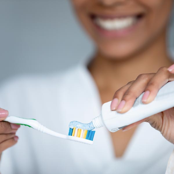 woman putting toothpaste on toothbrush
